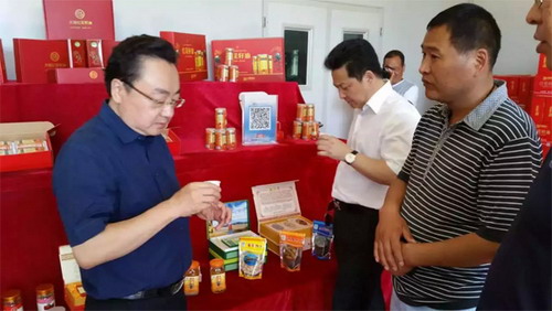 新疆裕民天鼎红花油有限公司董事长王来忠（右）陪宾客考察红花油产品及生产