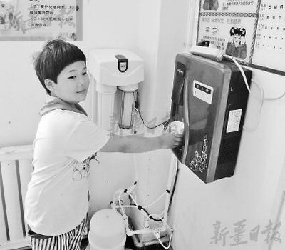库车县第12小学的学生陈芯蕊在新装的饮水机上接水 库车县第12小学的学生陈芯蕊在新装的饮水机上接水