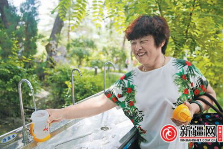 6月29日，一名游客正在红山公园山顶平台免费供水点接饮用水