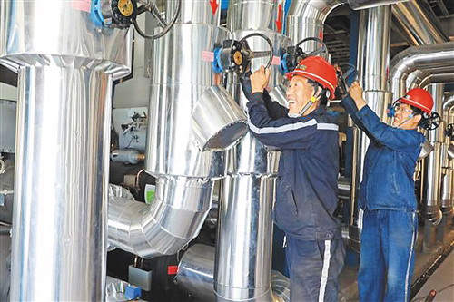 菏泽煤电公司郭屯煤矿原司炉工马延岭（左）在余热机房调试水量